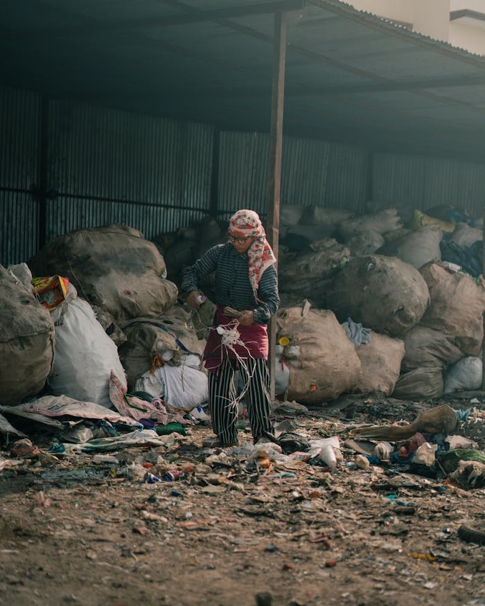 Female worker sorting trash at a recycling facility, promoting waste management.