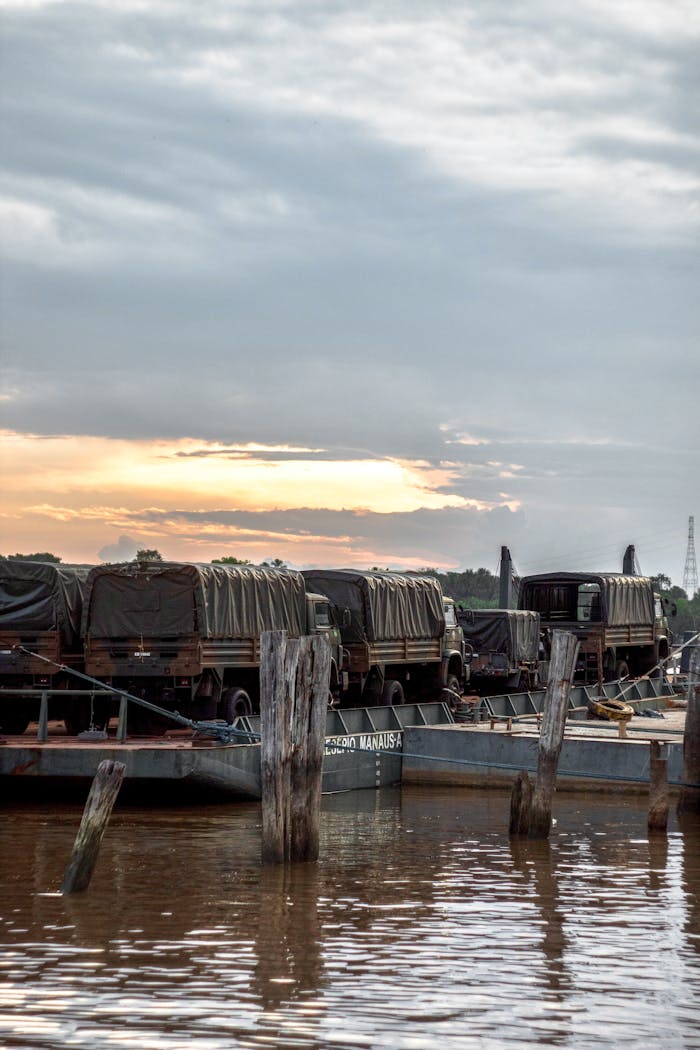 Barges carrying covered trucks moored on the river at sunset, Breves, Brazil.