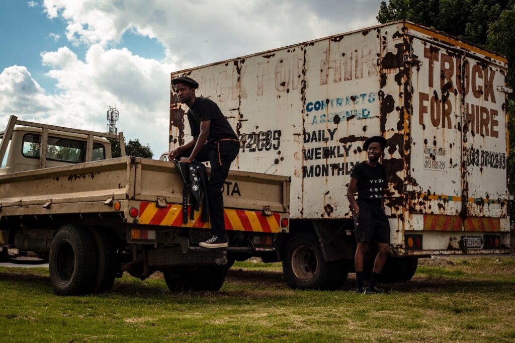Two African workers by transport trucks in Pimville, South Africa.